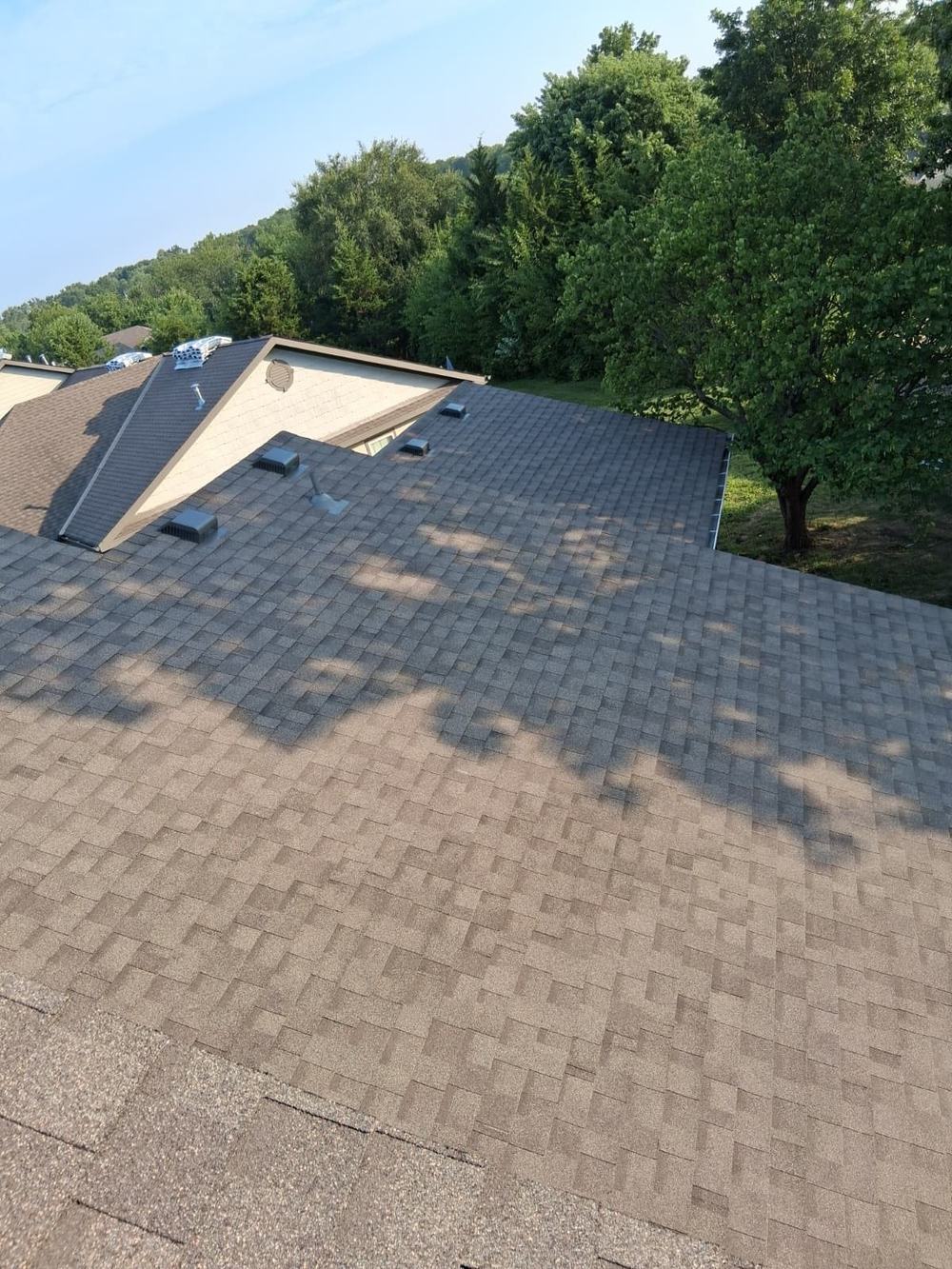 Newly installed brown architectural shingles on a shaded roof